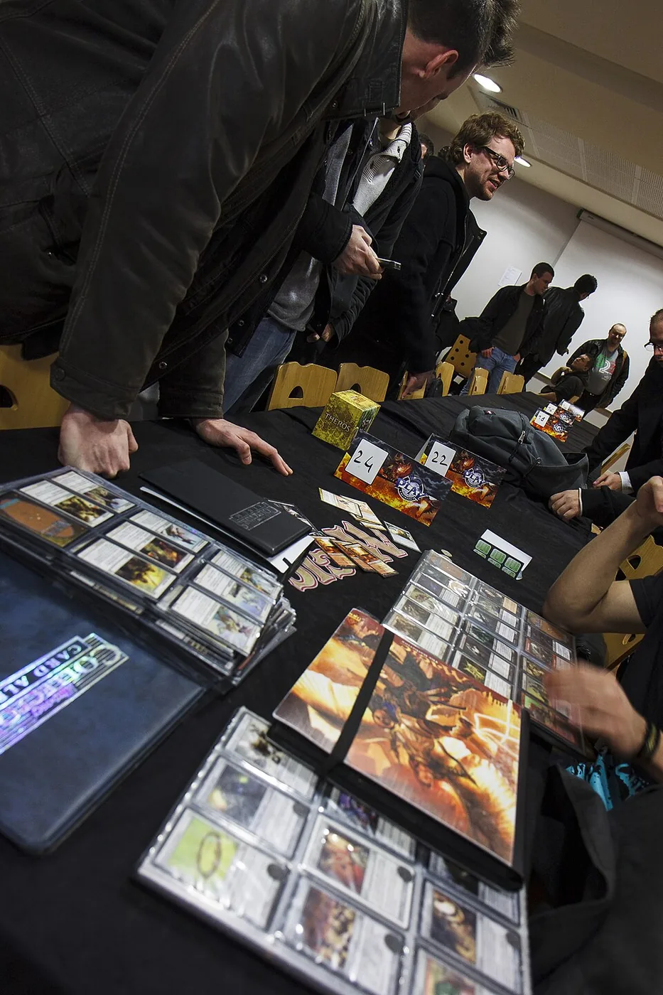 Adult collectors trading from open card binders at an event table