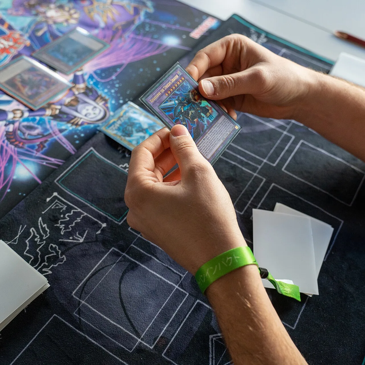 Hands sliding a card into a protective sleeve over a playmat