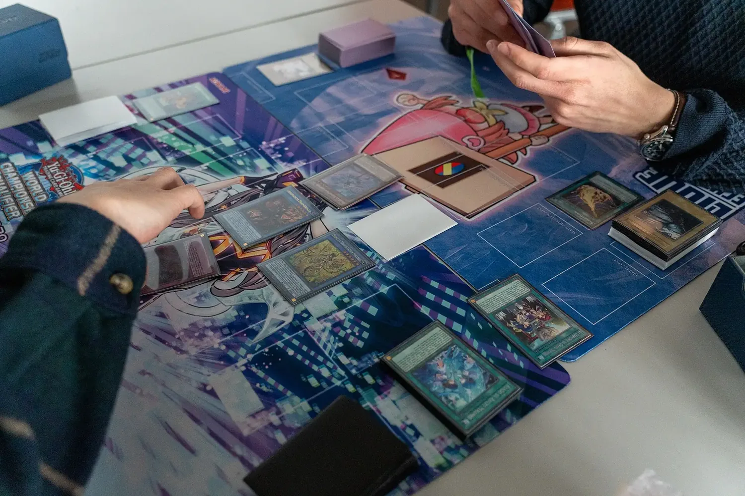 Players laying cards on playmats during a game